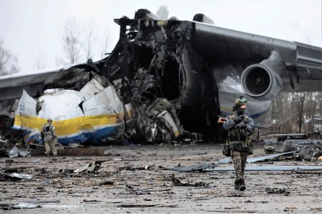 A Ukrainian service member walks in a front of an Antonov An-225 Mriya cargo plane, the world's biggest unique aircraft, destroyed by Russian troops at an airfield in the settlement of Hostomel, in Kyiv region, Ukraine on April 2, 2022. (Photo by Mikhail Palinchak/Reuters)