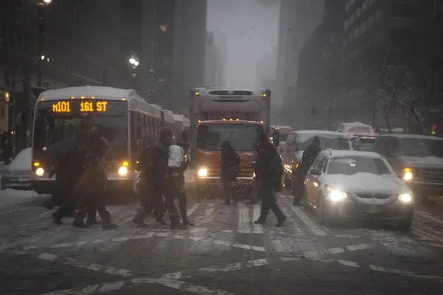 People cross a road as it snows in the Manhattan borough of New York January 26, 2015. (Photo by Carlo Allegri/Reuters)