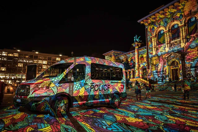A picture taken on December 14, 2020 evening shows a police van illuminated by the lightshow of “Festival Lausanne Lumières” at the Riponne place in the center of Lausanne, Switzerland. (Photo by Fabrice Coffrini/AFP Photo)