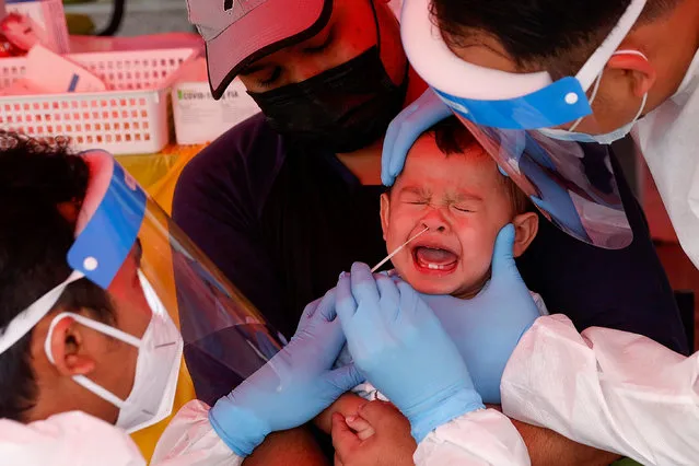 Medical personnel takes a swab sample for coronavirus testing from an infant in Shah Alam, outside Kuala Lumpur, Malaysia, 18 January 2021. An additional stimulus package worth in excess of three billion euro was announced by Malaysia Prime Minister Muhyiddin Yassin  known as “Malaysian Economic and People Protection Assistance Package (PERMAI). PERMAI initiative will be based on three main objections, which are to combat the Covid-19 pandemic, to ensure the welfare of the people, and to support the survival of businesses”, Muhyiddin said during a live telecast on 18 January 2021. (Photo by Fazry Ismail/EPA/EFE)