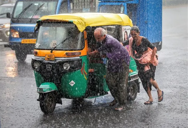 A couple push their auto rickshaw during heavy rains in Ahmedabad, India on June 26, 2023. (Photo by Amit Dave/Reuters)