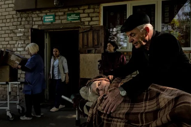 Volodymyr Yutin, 70, comforts his mother Katerina, 94, after they were both evacuated from the town of Lyman earlier in the day, as seen at a hospital in Kramatorsk, Ukraine, on Monday, May 9, 2022. Lyman is currently being contested by Ukrainian and Russian forces, and rescue workers are attempting to evacuate the remaining civilians. Approximately 150-200 are being evacuated by the Lyman rescue services. (Photo by Nicole Tung/The Washington Post)