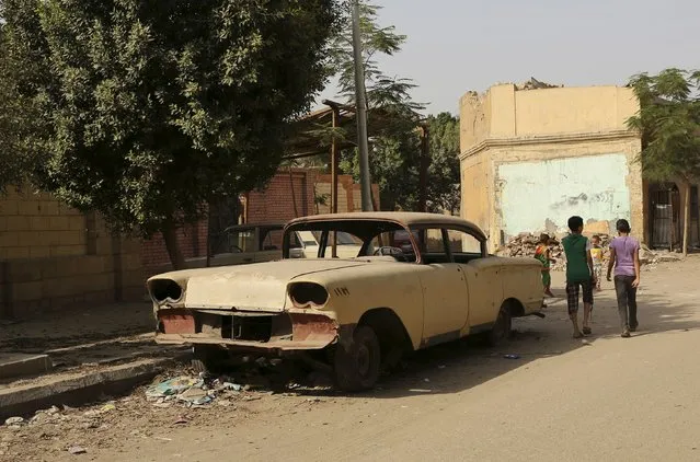 Children walk near an old car in a street in the Cairo Necropolis, Egypt, September 14, 2015. (Photo by Asmaa Waguih/Reuters)