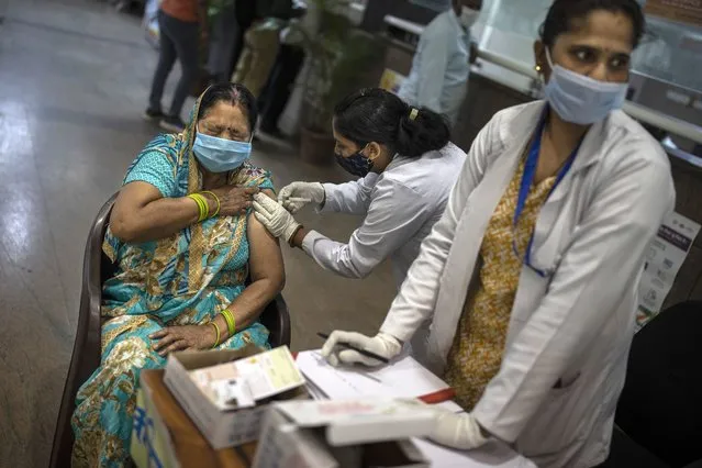 A woman receives a COVID- 19 vaccine at a government hospital in Noida, a suburb of New Delhi, India, Thursday, April 1, 2021. India is accelerating its vaccination drive by opening it up for everyone above 45 years just as cases spike sharply after several months. (Photo by Altaf Qadri/AP Photo)