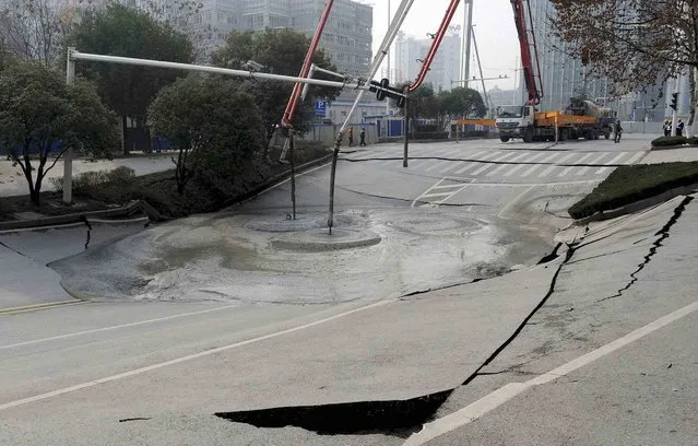 Workers use cement to fill in part of a road that caved in, in Wuhan, Hubei province February 11, 2015. (Photo by Reuters/China Daily)