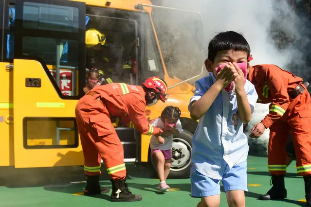 Firefighters instruct children evacuating a school bus during a fire drill at a kindergarten in Cangzhou, Hebei province, China on August 27, 2018. (Photo by Reuters/China Daily)