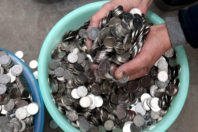 A man scoops a handful of one-yuan coins collected from coin-operated laundry machines, as he shows them to reporters in Zhengzhou, Henan province, China, January 11, 2016. (Photo by Reuters/Stringer)