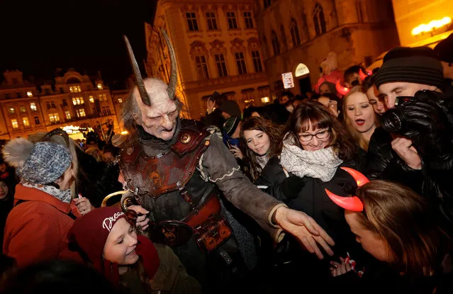 A reveller dressed as a devil gives sweets to children, on the eve of Saint Nicholas Day, at the Old Town Square in Prague, Czech Republic December 5, 2016. (Photo by David W. Cerny/Reuters)
