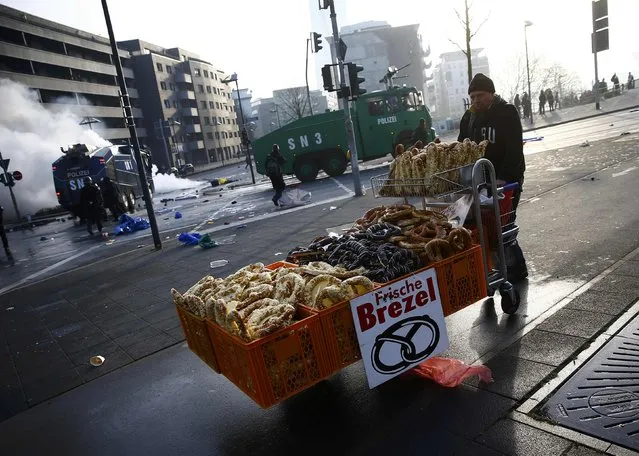 A street vendor passes by policemen during anti-capitalist “Blockupy” protest near the European Central Bank (ECB) building before the official opening of its new headquarters in Frankfurt March 18, 2015. (Photo by Kai Pfaffenbach/Reuters)