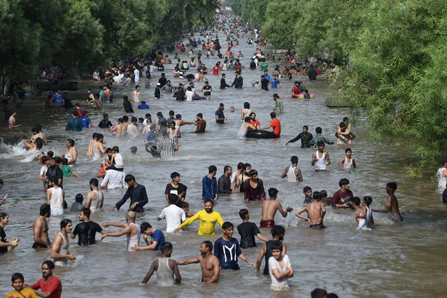 People cool themselves in a canal a hot summer day in Lahore on May 30, 2021. (Photo by Arif Ali/AFPPhoto)