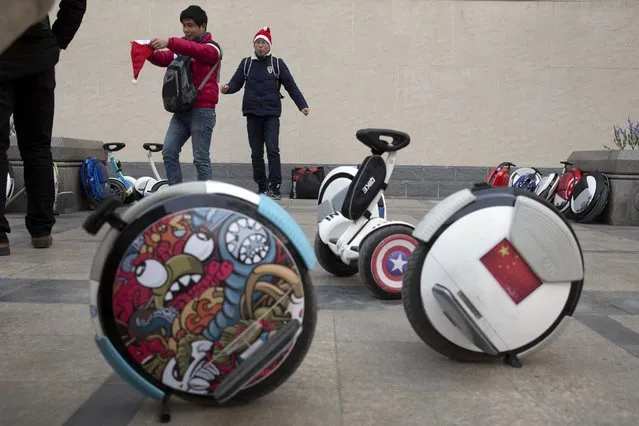 Chinese men put on Santa hats near electric unicycle scooters as a group of riders prepare to leave on a Christmas themed ride from a church in Beijing, China, Saturday, December 24, 2016. (Photo by Ng Han Guan/AP Photo)