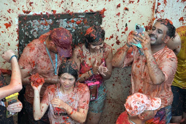 Revellers covered in tomato pulp take part in the annual “Tomatina” festival in the eastern town of Bunol, on August 31, 2022. The iconic fiesta, which is billed as “the world's biggest food fight” has become a major draw for foreigners, in particular from Britain, Japan and the United States. (Photo by Jose Jordan/AFP Photo)