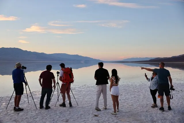 Visitors gather and take photos at the sprawling temporary lake at Badwater Basin salt flats, which was caused by flooding in August from Tropical Storm Hilary, at the recently reopened Death Valley National Park on October 21, 2023 in Death Valley National Park, California. The storm delivered a year's worth of rain to Death Valley in a single day and flood damage forced the iconic desert park's closure for eight weeks. Death Valley is the hottest place on Earth and Badwater Basin is located 282 feet below sea level, the lowest elevation in North America. Parts of the park remain closed as repair work continues. (Photo by Mario Tama/Getty Images/AFP Photo)