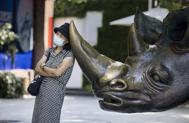 A woman wearing a mask for protection stands by a sculpture in the park in Shanghai, China, 06 August 2021. The China National Health Commission on 06 August reported 124 new confirmed COVID-19 cases. It is the highest daily count in the current outbreak. Some 80 new locally transmitted cases were reported in Mainland China, of which 61 were recorded in the Jiangsu province the day befor on 05 August. (Photo by Alex Plavevski/EPA/EFE)