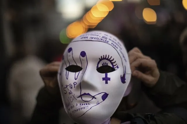 A women wearing a mask reading “Stop VOX” attends a rally to mark the International Women's Day in Madrid, Friday, March 8, 2019. Thousands of women walked off the job in Spain, joining millions more around the world demanding equality amid a persistent salary gap, violence and widespread inequality. VOX is Spain's far-right political party. (Photo by Bernat Armangue/AP Photo)