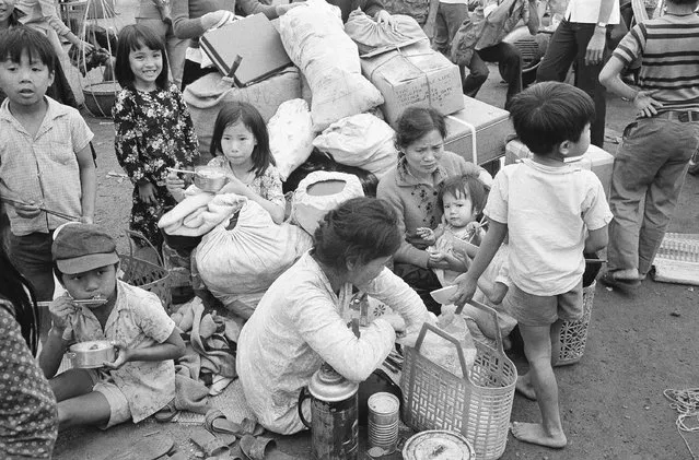 Their household goods in a haphazard pile, a South Vietnamese refugee family takes time out for lunch at Da Nang in Vietnam, March 28, 1975, where they are waiting to be relocated after fleeing from the Northern provinces. (Photo by AP Photo/Phuoc)
