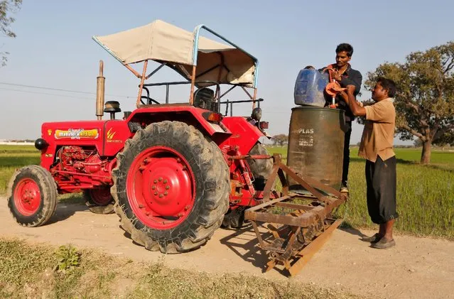 Farmers transfer diesel from a drum to a jerrycan which will be used to run a diesel water pump for irrigation at a paddy field on the outskirts of Ahmedabad, India, February 1, 2017. (Photo by Amit Dave/Reuters)