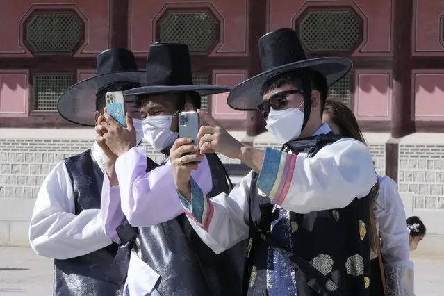 Men wearing face masks as a precaution against the coronavirus take photos as they visit to celebrate Chuseok holidays, the Korean version of Thanksgiving Day, at the Gyeongbok Palace in Seoul, South Korea, Wednesday, September 22, 2021. (Photo by Ahn Young-joon/AP Photo)