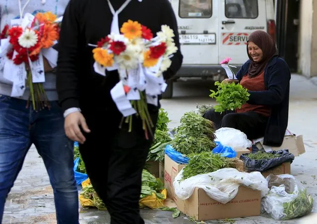 A herb vendor smiles after receiving a flower from leftist politically affiliated youths during International Women's Day at the port city of Sidon, southern Lebanon March 8, 2016. (Photo by Ali Hashisho/Reuters)
