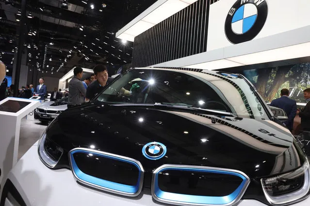 A worker cleans an electric vehicle at the BMW booth during the Auto Shanghai 2019 show in Shanghai Wednesday, April 17, 2019. Automakers are showcasing electric SUVs and sedans with more driving range and luxury features at the Shanghai auto show, trying to appeal to Chinese buyers in their biggest market as Beijing slashes subsidies that have propelled demand. (Photo by Ng Han Guan/AP Photo)