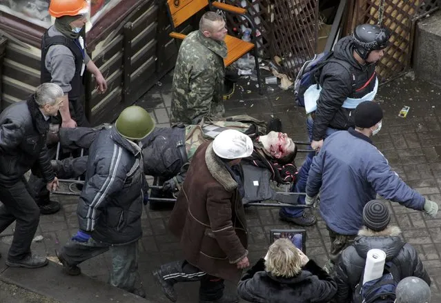 Anti-government protesters carry an injured man on a stretcher after violence erupted in the Independence Square in Kiev February 20, 2014. (Photo by Konstantin Chernichkin/Reuters)
