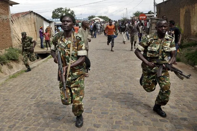 Soldiers run after demonstrators protesting President Pierre Nkurunziza's decision to seek a third term in office who caught and stoned a suspected Imbonerakure militiaman in the Cibitoke district of Bujumbura, Burundi, Thursday May 7, 2015. (Photo by Jerome Delay/AP Photo)