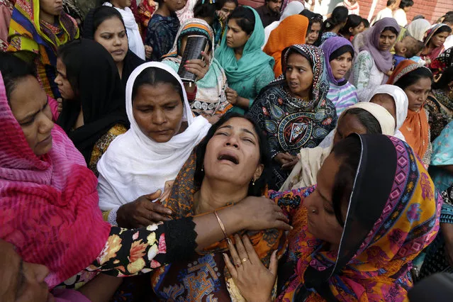 People try to comfort a Pakistani Christian mother during the funeral of her two daughters, killed in a suicide bombing Sunday, in Lahore, Pakistan, Thursday, March 30, 2016. The massive suicide bombing by a breakaway Taliban faction targeted Christians gathered for Easter Sunday in a park in Lahore, killing at least 70 people, mostly Muslims. (Photo by K.M. Chaudary)/AP Photo