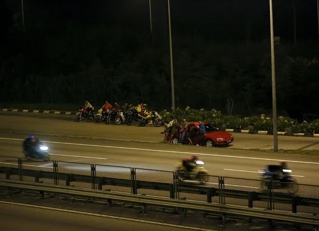 Spectators watch motorbike racing on a highway in Kuala Lumpur, Malaysia, April 19, 2015. (Photo by Olivia Harris/Reuters)