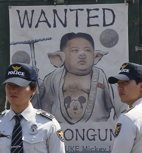 A banner depicting North Korean leader Kim Jong Un as a pig is displayed against international women activists before the activists arrive at the Imjingak Pavillion near the border village of Panmunjom in Paju, South Korea, Sunday, May 24, 2015. International women activists including Gloria Steinem and two Nobel Peace laureates on Sunday were denied an attempt to walk across the Demilitarized Zone dividing North and South Korea. (Photo by Ahn Young-joon/AP Photo)