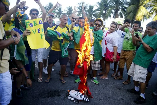 Demonstrators burn a flag of Brazilian President Dilma Rousseff's party, PT (Workers Party), during a protest against her in Copacabana beach in Rio de Janeiro, Brazil April 17, 2016. (Photo by Pilar Olivares/Reuters)