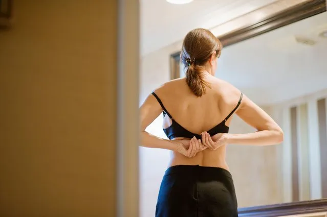 A woman that is standing in front of a mirror, bra strap, view from back. (Photo by Rex Features/Shutterstock)