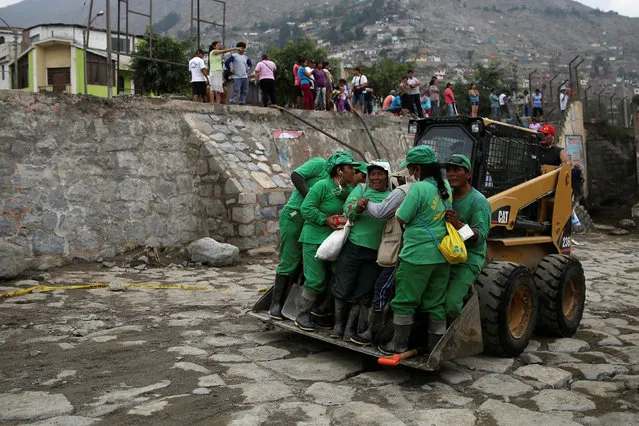 A loader carries a group of workers from the municipality of Chosica after a landslide and flood in Chosica, east of Lima, Peru on March 17, 2017. (Photo by Guadalupe Pardo/Reuters)