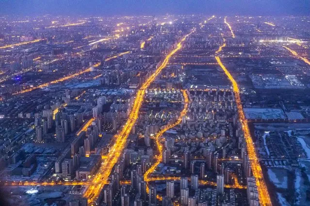 Arterial roads are lit up as morning commuters drive along at dawn in western Beijing on January 31, 2022 ahead of the Beijing 2022 Winter Olympic Games. (Photo by Odd Andersen/AFP Photo)