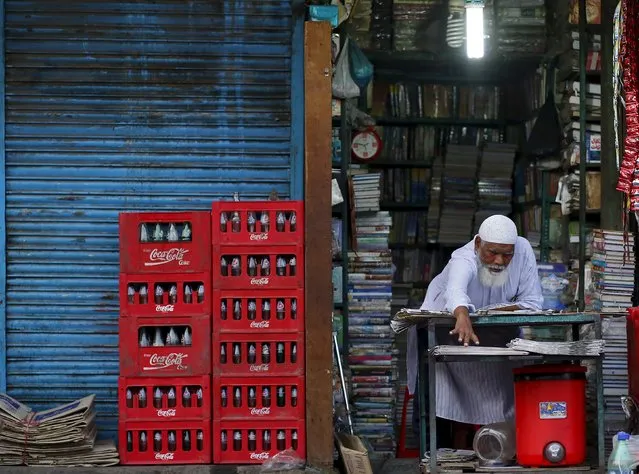 A shopkeeper extends his hand as he arranges newspapers for sale at his shop during early morning in the old quarters of Delhi, India, July 2, 2015. (Photo by Anindito Mukherjee/Reuters)