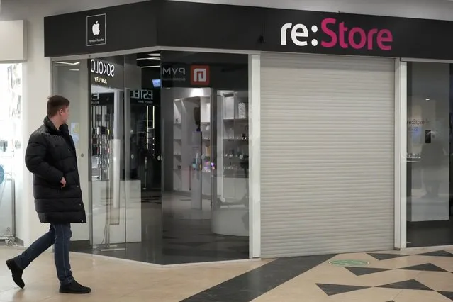 A man walks past a closed “re:Store”, an Apple reseller shop at a shopping mall in St. Petersburg, Russia, Wednesday, March 2, 2022. Apple announced that it would stopped selling its iPhone and other popular products in Russia along with limiting services like Apple Pay as part of a larger corporate backlash to protest the invasion. Dozens of foreign and international companies have pulled their business out of Russia. (Photo by Dmitri Lovetsky/AP Photo)
