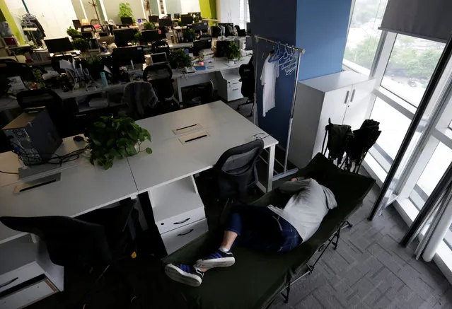 Kou Meng, product manager of RenRen Credit Management Co., sleeps on a camp bed at the office early morning, in Beijing, China, April 27, 2016. (Photo by Jason Lee/Reuters)