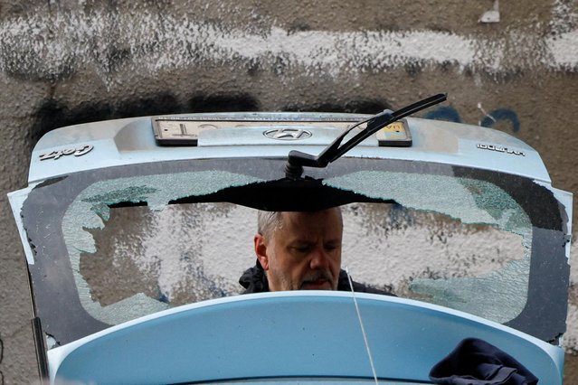 A man checks a damaged car at the site of a Russian missile strike, amid Russia's attack on Ukraine, in Kyiv, Ukraine on March 9, 2023. (Photo by Gleb Garanich/Reuters)