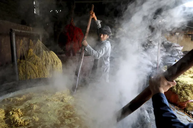 Laborers stir a vat of wool at a dyeworks, in Kabul, Afghanistan, Tuesday, October 1, 2019. The yarn will be used in making hand-knotted carpet. (Photo by Ebrahim Noroozi/AP Photo)