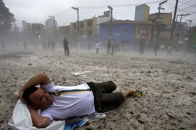 A man lies for fun on a layer of hail in a street after a hailstorm in the Aclimacao neighborhood in Sao Paulo, Brazil on May 19, 2014. After the severe overnight hailstorm a layer of hailstones as deep as 20 centimeters covered streets and parks, drawing people to make snowmen and play in the ice, an unusual scene to the city. (Photo by Nelson Almeida/AFP Photo)