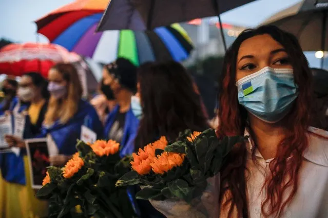 A protester holds flowers near Independence Square during a protest over Russia's invasion of Ukraine, in Kuala Lumpur, Malaysia, 05 March 2022. Russian troops entered Ukraine on 24 February prompting the country's president to declare martial law and triggering a series of severe economic sanctions imposed by Western countries on Russia. (Photo by Fazry Ismail/EPA/EFE/Rex Features/Shutterstock)