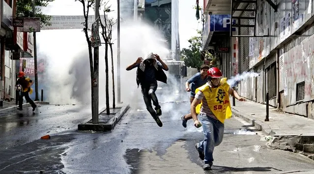 Protestors run away from tear gas used by Turkish riot police during a demonstration against the government in Istanbul, Turkey, 22 May 2014. A group of protestors see the Turkish government responsible for the Soma mine explosion. Prime Minister Recep Tayyip Erdogan's AKP reportedly rejected a motion by the centre-left People's Republican Party (CHP) in April to review safety at the Soma mine. The worst mining disaster in the country's history left at least 301 workers dead. (Photo by Ulas Yunus Tosun/EPA)