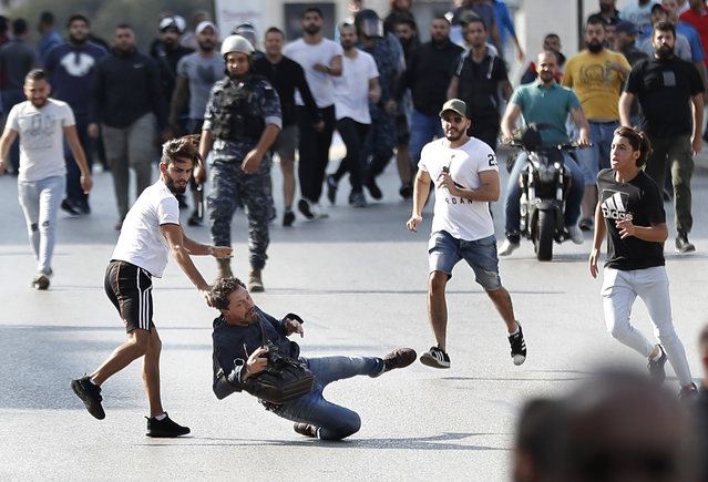A French photographer is attacked by Hezbollah supporters while covering clashes between them and anti-government protesters, in Beirut, Lebanon, Tuesday, October 29, 2019. The violence came shortly after dozen others, wielding sticks, attacked a roadblock on a main Beirut thoroughfare set up by the protesters. (Photo by Hussein Malla/AP Photo)