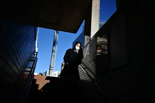 A woman walks down the stairs of a train station in Tokyo's Ginza district on October 23, 2019. (Photo by Charly Triballeau/AFP Photo)