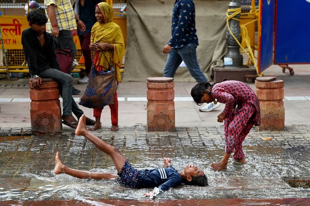 Children play in a puddle of water after rainfall in the old quarters of Delhi on August 8, 2024. (Photo by Sajjad Hussain/AFP Photo)