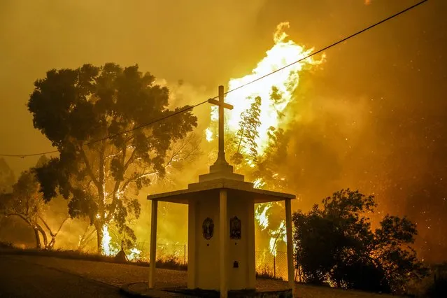 Flames rise next to a church during a fire in Pampilhosa da Serra, central of Portugal, 18 June 2017. At least sixty two people have been killed in forest fires in central Portugal, with many being trapped in their cars as flames swept over a road on the evening of 17 June 2017. (Photo by Paulo Novais/EPA)