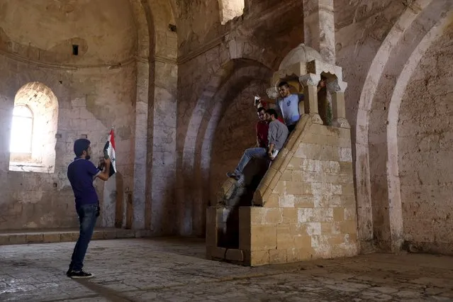 Visitors pose for a picture as one of them holds the Syrian national flag inside the Crac des Chevaliers, a UNESCO World Heritage site, in the Homs countryside, Syria August 2, 2015. (Photo by Omar Sanadiki/Reuters)