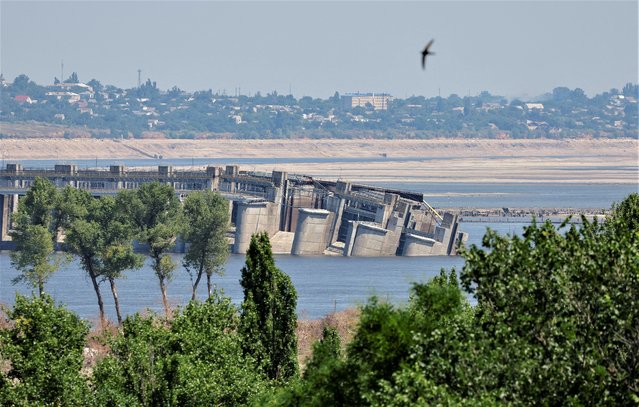 The destroyed Nova Kakhovka dam, Beryslav town and Dnipro river bank, dried-up after water level sharply dropped following the collapse of the dam in the course of the Russia-Ukraine conflict, are seen from the town of Nova Kakhovka in Kherson region, Russian-controlled Ukraine on July 5, 2023. (Photo by Alexander Ermochenko/Reuters)