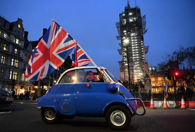 A man waves Union flags from a small car as he drives past Brexit supporters gathering in Parliament Square, near the Houses of Parliament in central London on January 31, 2020 on the day that the UK formally leaves the European Union. Britain on January 31 ends almost half a century of integration with its closest neighbours and leaves the European Union, starting a new – but still uncertain – chapter in its long history. (Photo by Daniel Leal-Olivas/AFP Photo)