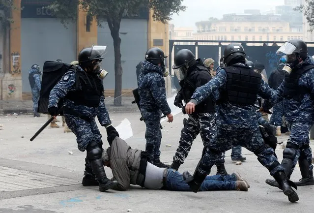 A riot police officer pulls a protestor lying on the ground during a protest seeking to prevent MPs and government officials from reaching the parliament for a vote of confidence, in Beirut, February 11, 2020. (Photo by Mohamed Azakir/Reuters)