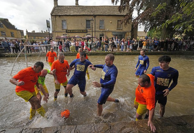 Footballers from Bourton Rovers fight for the ball during the annual traditional River Windrush football match, which has been taking place for over 100 years, in the Cotswolds village of Bourton-on-the-Water, England, Monday, August 28, 2023. The event sees two teams of six from Bourton Rovers Football Club play a 30 minute football match in the usually calm river water. Goalposts are set up in the river and players attempt to score as many goals as possible, whilst getting all spectators as wet as possible in the process. (Photo by Frank Augstein/AP Photo)